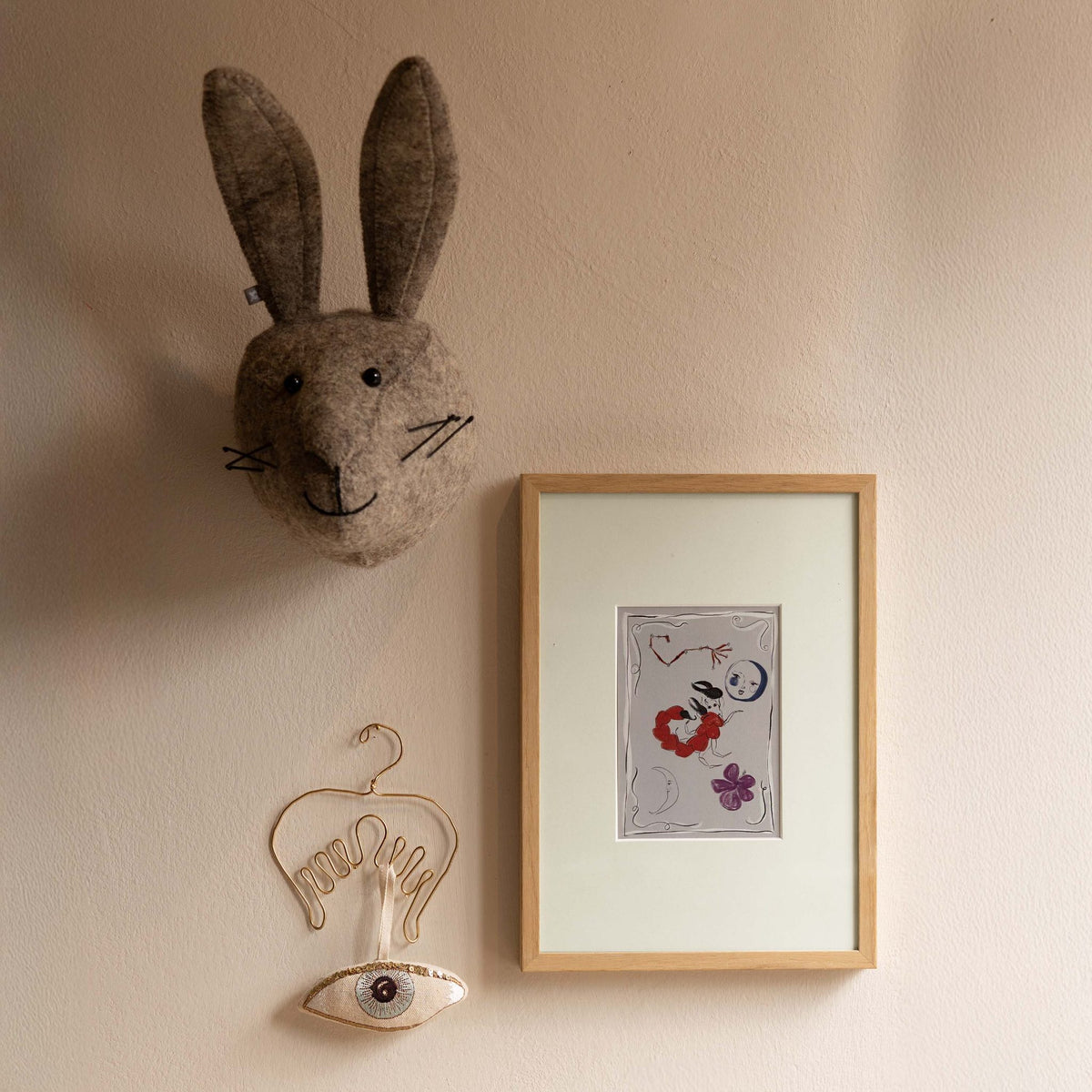 Ingelijste Hazel &amp; George Schorpioen-poster aan de wand, naast een knuffelkonijnenkop en een hangende oog-decoratie