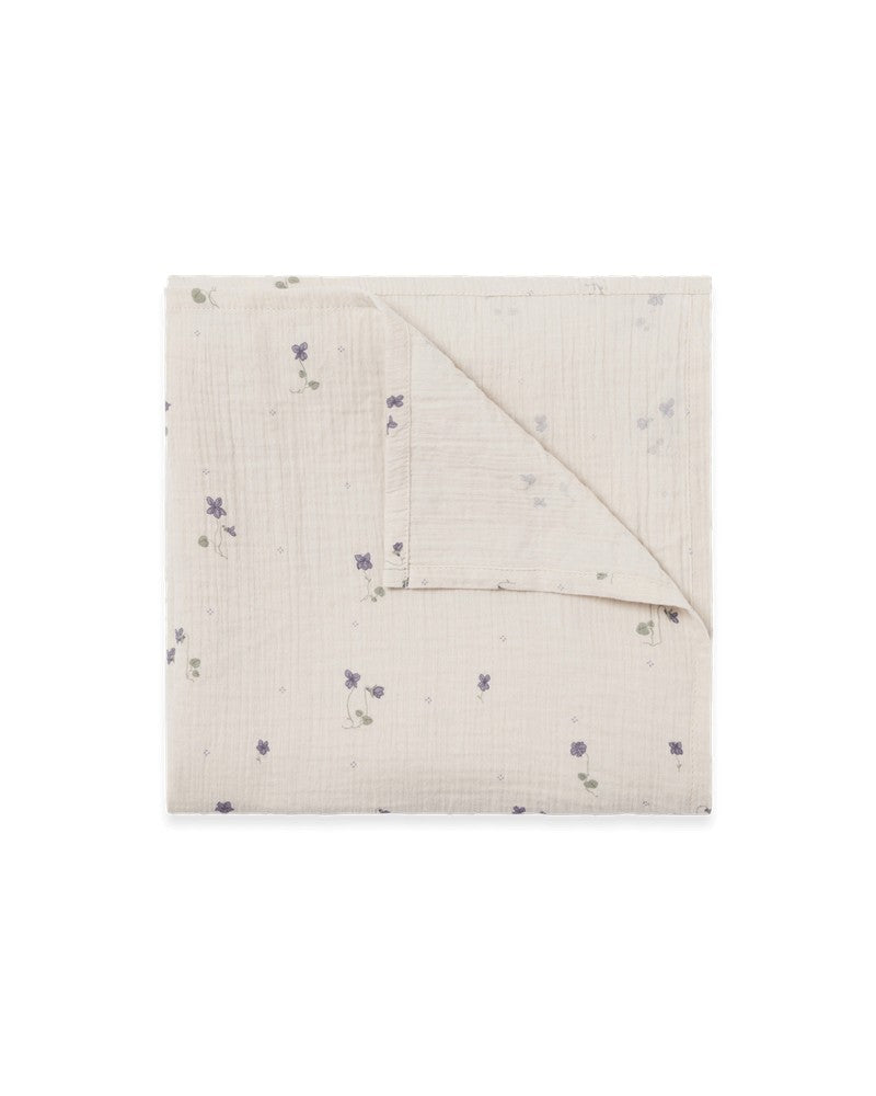 A beige swaddle blanket with a small blue dot pattern, folded neatly.