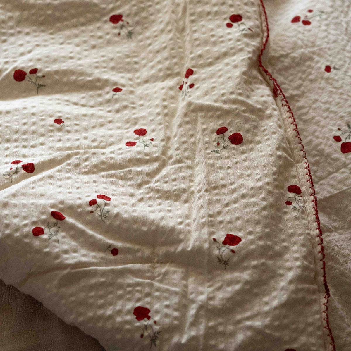 Close-up of the Garbo&amp;Friends Filled Blanket in Seersucker Poppy, showing the quilted seersucker fabric