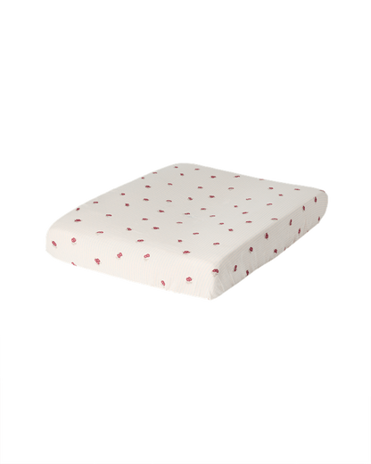 Garbo &amp; Friends Muslin Changing Mat Cover Rosehip on a changing pad, ivory organic cotton muslin with small rosehip-red flowers