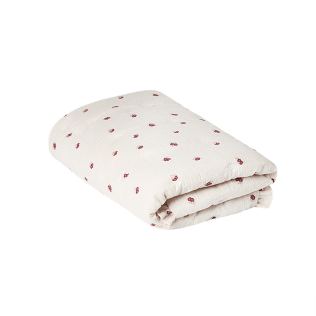 A folded muslin blanket in off-white with a small red floral pattern
