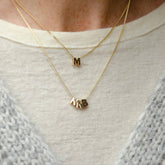 Hazel & George Chunky Initial 14K Gold, layered gold necklaces worn on a sweater with chunky letter charms spelling M and NRB