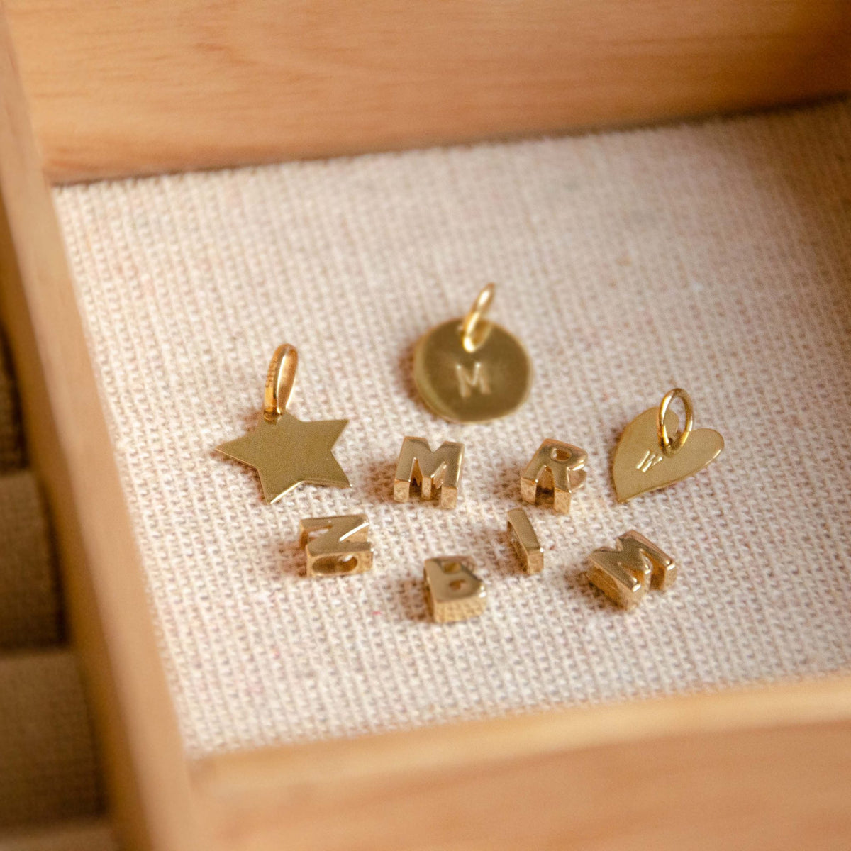 Hazel &amp; George Chunky Initial 14K Gold, assortment of gold charms in a jewelry box, including a star, a round disc, a heart and chunky bubble letters