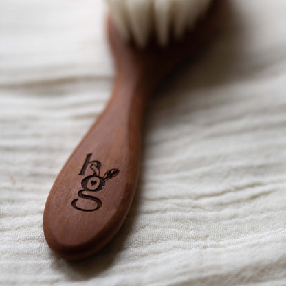 Close-up of the engraved Hazel &amp; George logo on the wooden handle of the baby hair brush