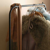 Close-up of the Hazel & George Dazzling Disco Ball Large rose ribbon knotted on a clothing rail with a faux fur coat and dress-up costumes