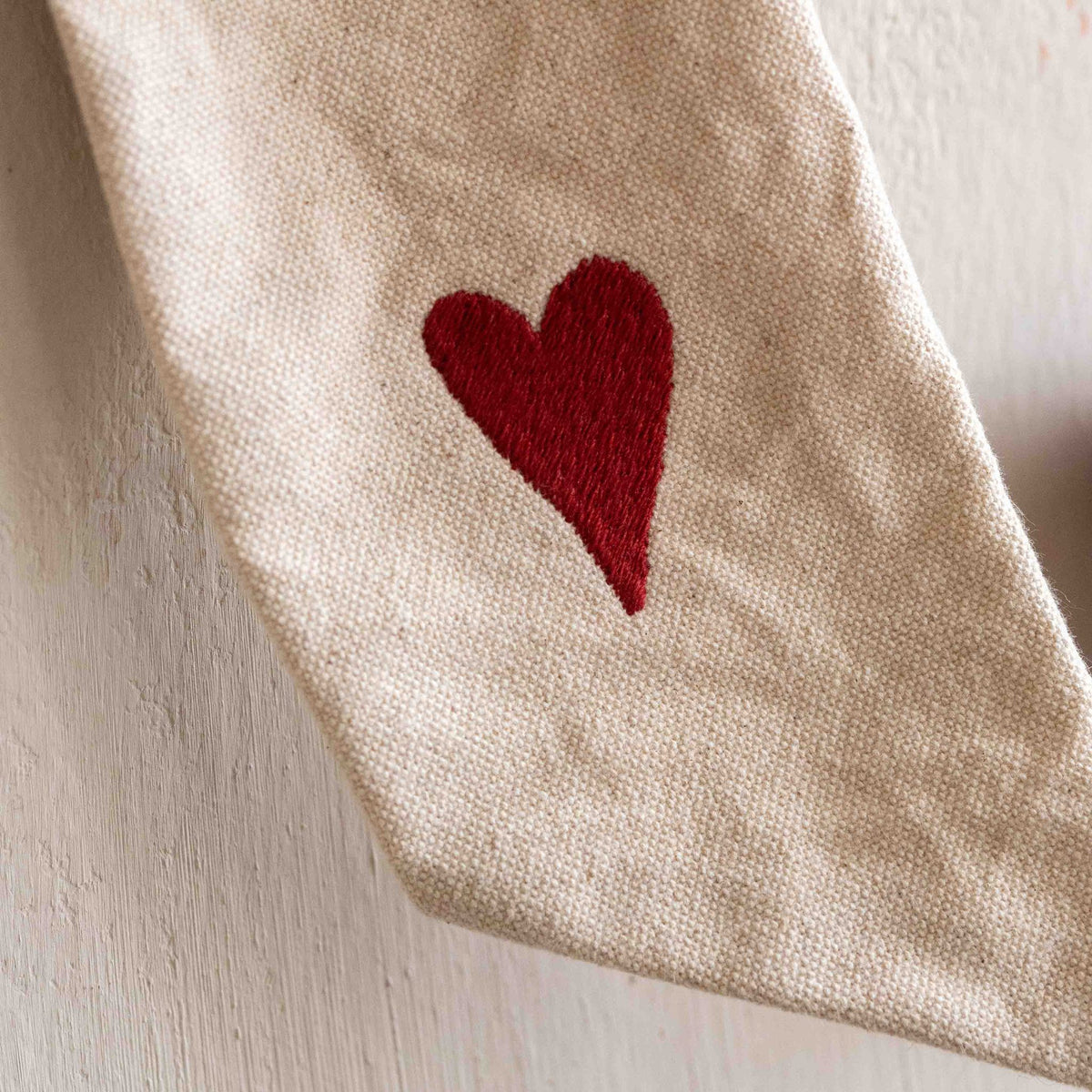 Extreme close-up of the embroidered red heart on the tail of a Hazel &amp; George Canvas Festive Bow Small