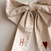 Close-up of the knot detail on a Hazel & George Canvas Festive Bow Small, embroidered with the initial H and a red heart