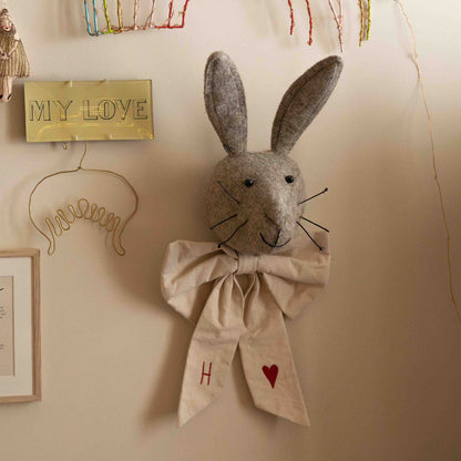 Hazel &amp; George Canvas Festive Bow Small tied around a plush rabbit head wall decoration, styled with other nursery wall decor