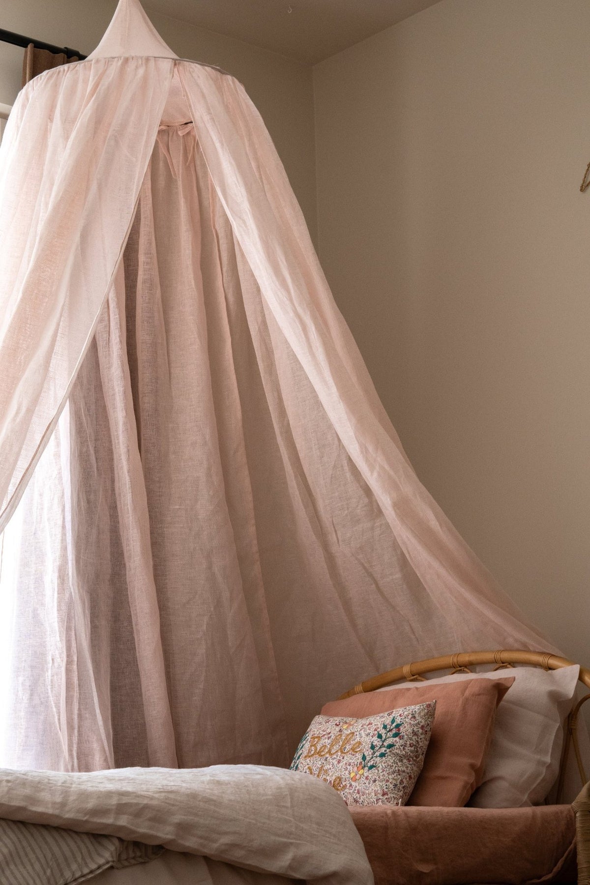 Hazel &amp; George Linen Bed Canopy in Craie hanging over a rattan bed with a &
