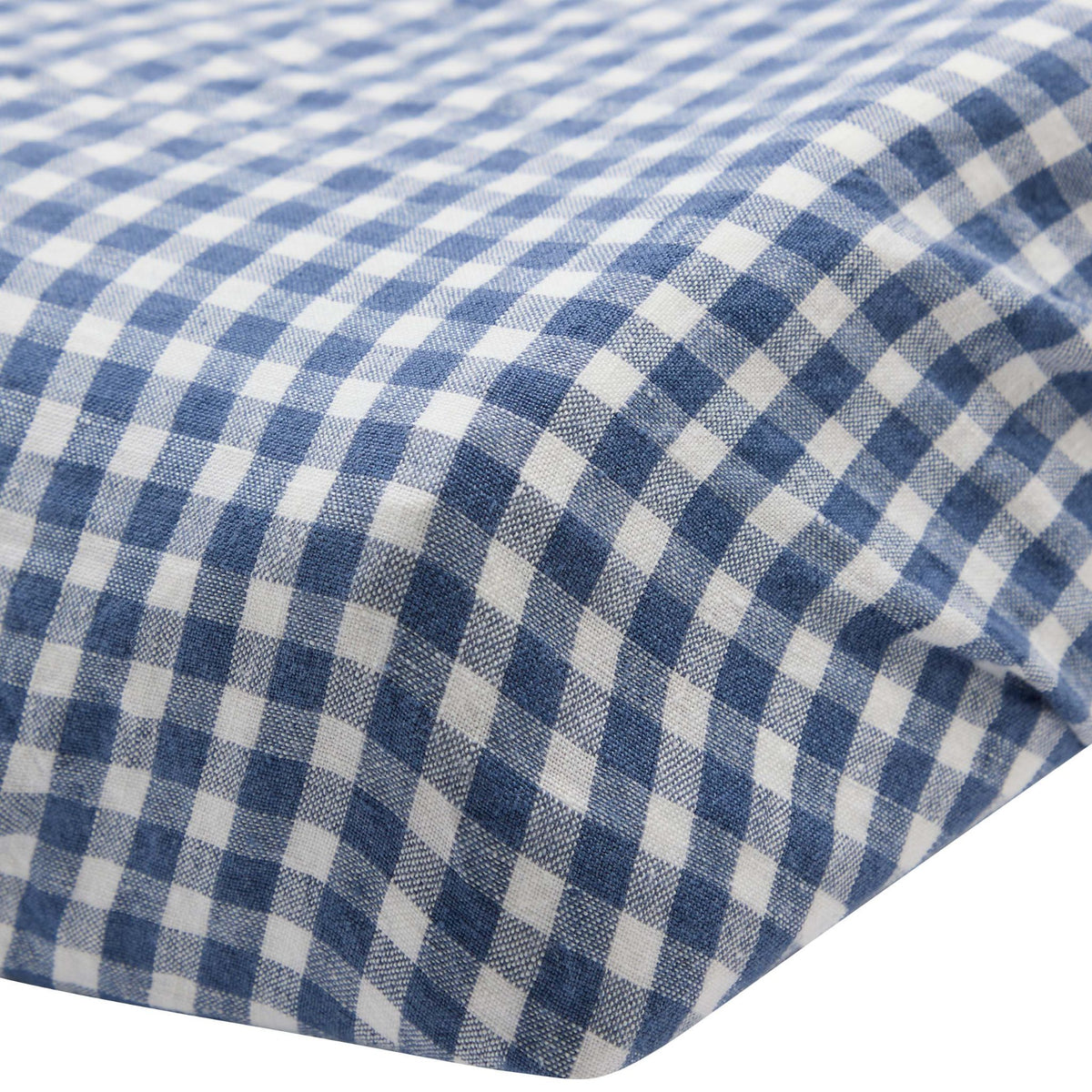 Close-up of the corner of the Hazel &amp; George Linen Changing Mat Cover in Vichy, showing the blue-and-white check fabric and fitted edge