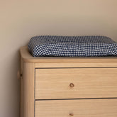 Hazel & George Linen Changing Mat Cover in Vichy on top of a wooden dresser, used as a changing table