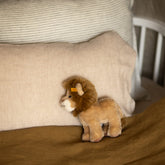 Nursery crib styled with a Hazel & George linen cushion in Naturel, a striped pillow, and a plush lion toy