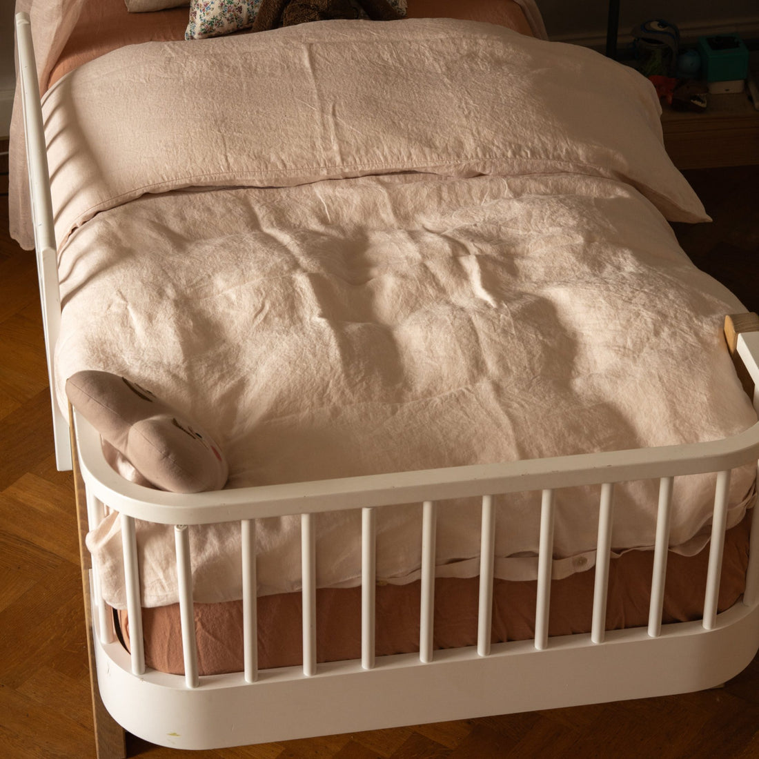 Hazel &amp; George Linen Duvet Cover in Craie on a toddler bed with a bed rail, with a matching pillow