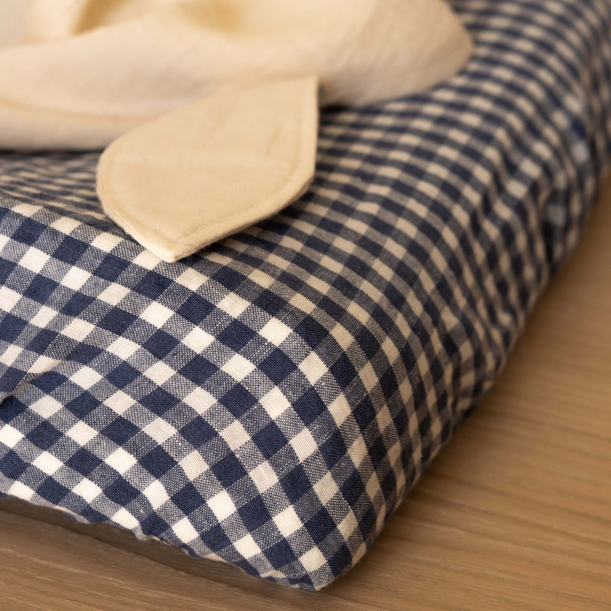 Close-up of the elastic corner of the Hazel &amp; George Fitted Sheet in Vichy, with a natural muslin cloth folded on top