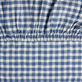 Close-up of the elastic corner of the Hazel & George Fitted Sheet in Vichy, showing the woven blue-and-white check pattern