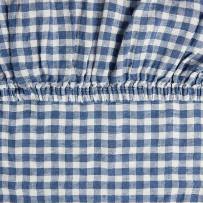 Close-up of the elastic corner of the Hazel &amp; George Fitted Sheet in Vichy, showing the woven blue-and-white check pattern