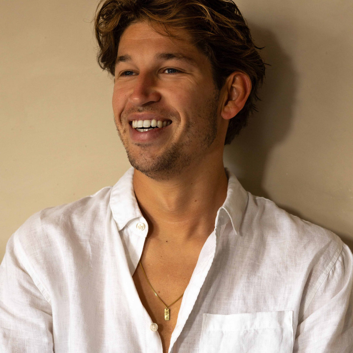 Hazel &amp; George Rectangular Initial Hanger 14K Gold, smiling man wearing the rectangular gold pendant necklace with a white linen shirt