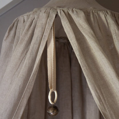 Close-up of the top of the Hazel &amp; George Linen Bed Canopy in Naturel, with the hanging strap, ring and decorative bell