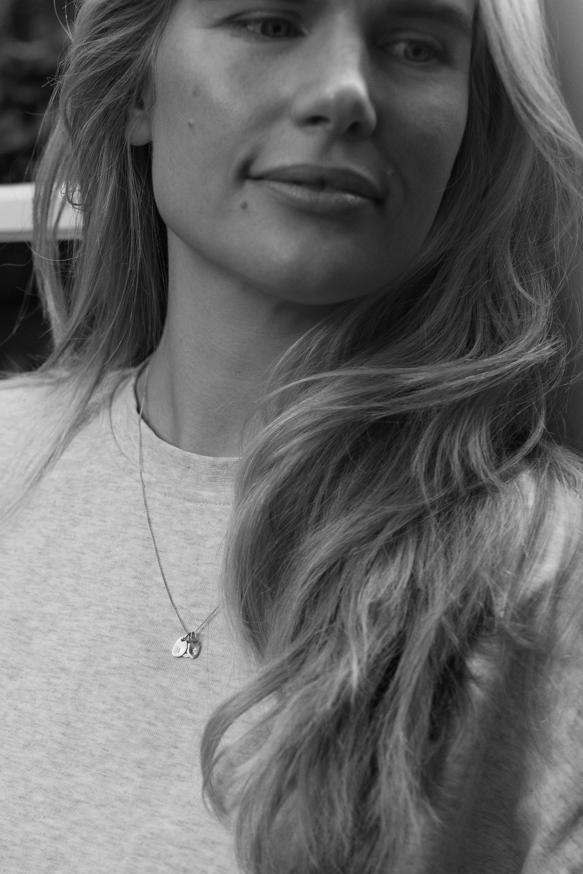 Hazel &amp; George Necklace 14K Gold with small initial hangers, worn by a woman in a grey sweatshirt