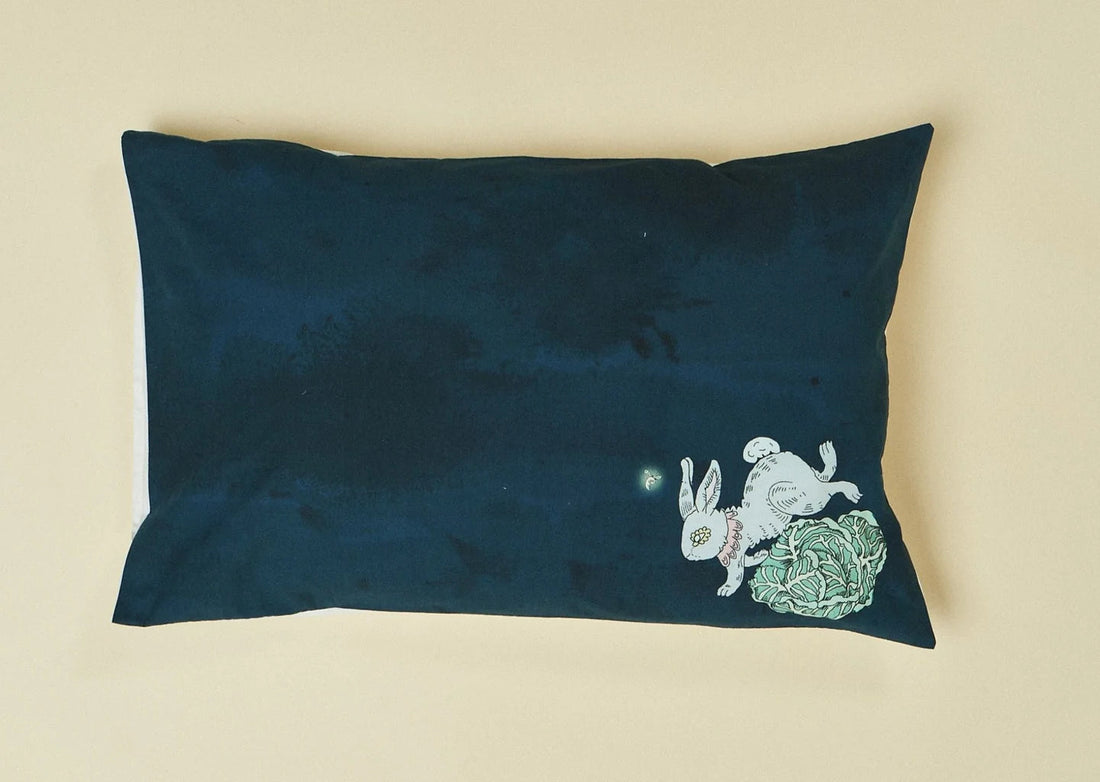 Dark blue pillow with printed design of a rabbit and cabbage