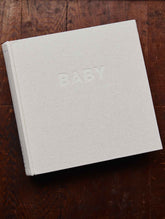 Write to me Fotoalbum Classic Baby met naturel linnen kaft en BABY in reliëf, op een houten tafel